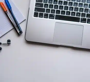 silver laptop computer beside white ruled paper