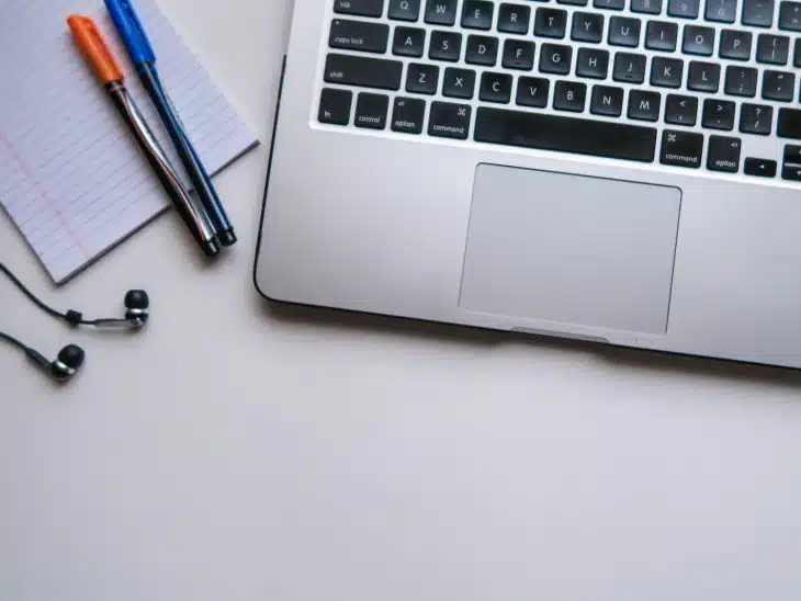 silver laptop computer beside white ruled paper